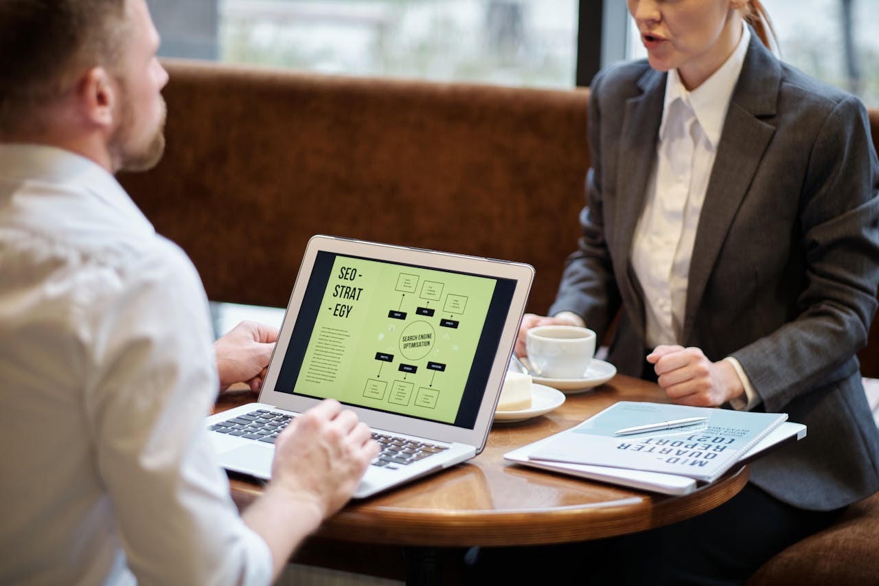 Mastering the First Impression: Your intriguing post title goes here A man and woman engaged in a business meeting discussing SEO strategy in a cozy cafe setting.